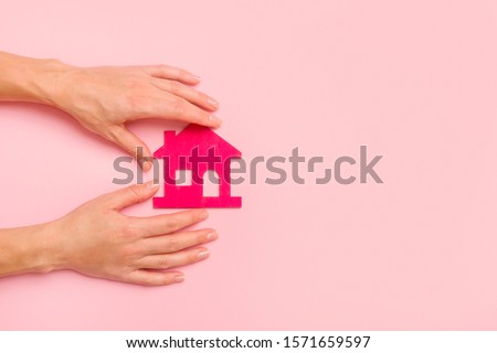 Hand Holding Pink house on pink background. New home concept