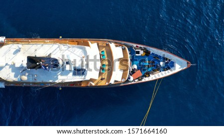 Aerial drone top down photo of luxury yacht with wooden deck docked in open ocean bay with deep blue sea