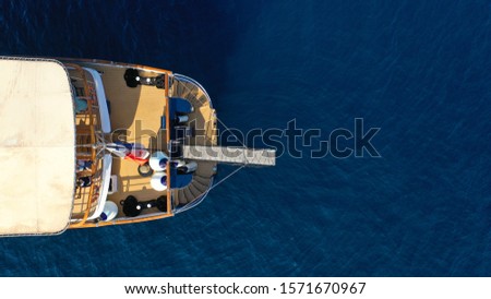 Aerial drone photo of luxury yacht docked in deep blue sea near old port of Fira of Santorini island, Cyclades, Greece