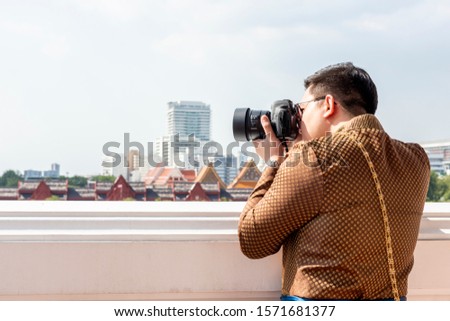 A Man looking into DSLR camera and taking photo of Bangkok landscape.