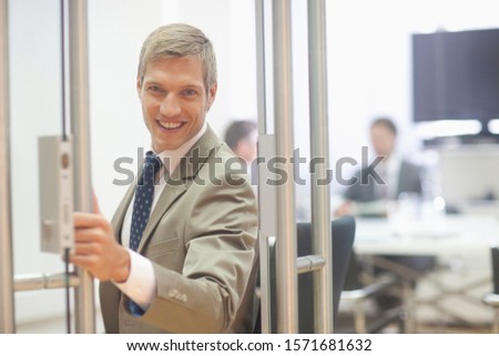 Businessman at door of meeting room, smiling, portrait