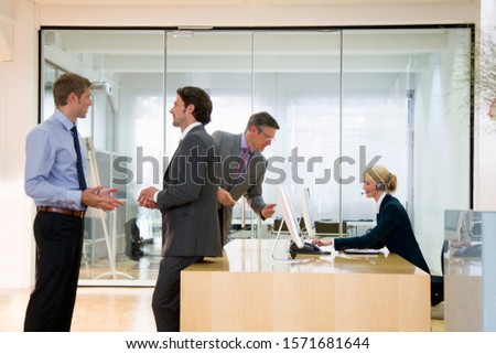 Businessmen in discussion in office with secretary