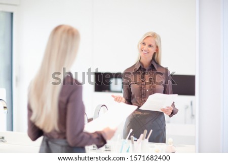 Young businesswoman practicing presentation in mirror Royalty-Free Stock Photo #1571682400
