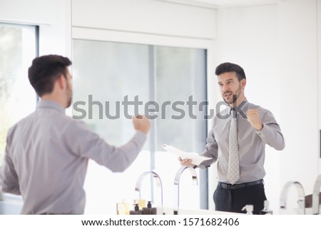 Mid adult businessman practicing presentation in mirror Royalty-Free Stock Photo #1571682406