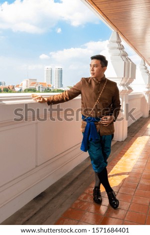 A Man dressed in Thai traditional dress, with a view of Bangkok landscape.