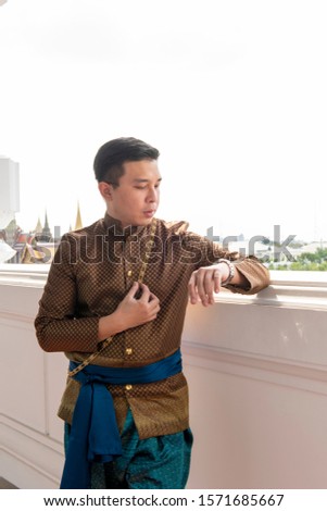 A Man dressed in Thai clothes, looking at the clock.