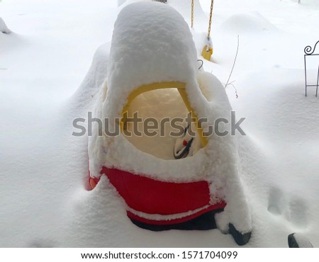 Child size toy car covered in a blanket of snow after serious snow storm in Colorado