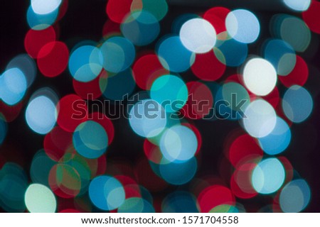Unfocused photo of christmas garland with colorful lights. Abstract  background of circles in bokeh.
