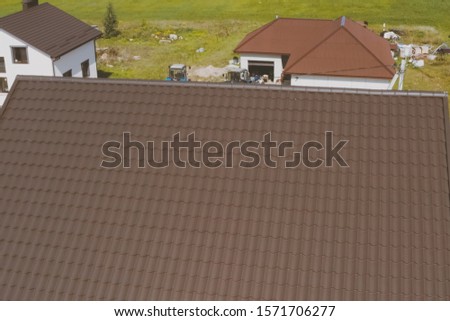 Modern roof made of metal. Brown metal tile on the roof of the house. Corrugated metal roof and metal roofing.