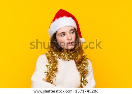 Girl with christmas hat over isolated yellow background thinking an idea
