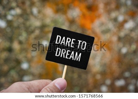 Dare To Dream. Hand Holding Stick Blackboard.
