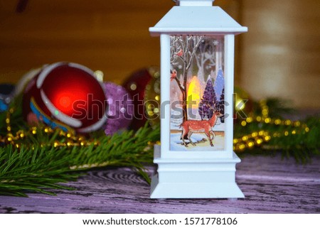 close-up of a white Christmas lantern with a picture of a deer on a wooden table