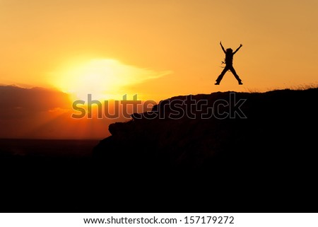 Silhouette of jumping woman with backpack, sunset sky as a background 