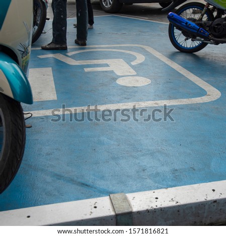 Motorbikes parked in a disability zone parking only even though a restricted graphic sign printed clearly seen on the floor. Motor-bikers seems not to car what they have done against the laws.