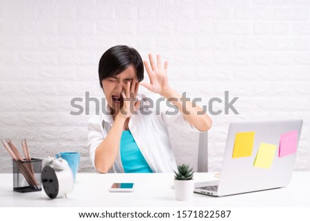 Woman sitting at home office working using computer laptop and shocking and scared something