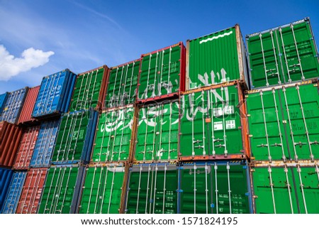 The national flag of Saudi Arabia
 on a large number of metal containers for storing goods stacked in rows on top of each other. Conception of storage of goods by importers, exporters