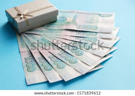 Russian money, Russian rubles 1000 and gift box with gold bow on a blue background. Concept of wealth. Increasing income. Winning the lottery. Selective focus