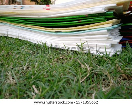 Isolated Non Woven light colors Bags on Green Grass Background