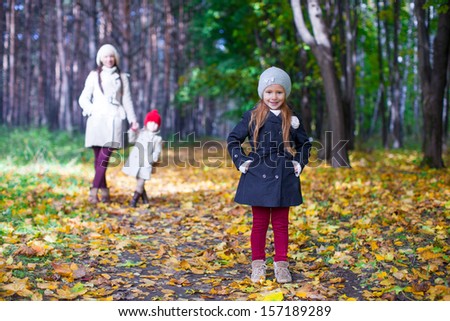 Young mother and her adorable daughter walking in yellow autumn forest on a warm sunny day