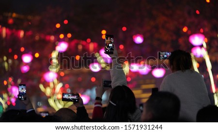 The people taking picture for the hot show with their phones  in the Chinese city at night