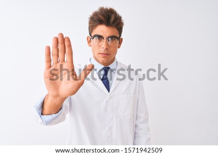 Young handsome sciencist man wearing glasses and coat over isolated white background doing stop sing with palm of the hand. Warning expression with negative and serious gesture on the face.
