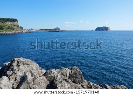 an island and a lighthouse against blue sea and sky