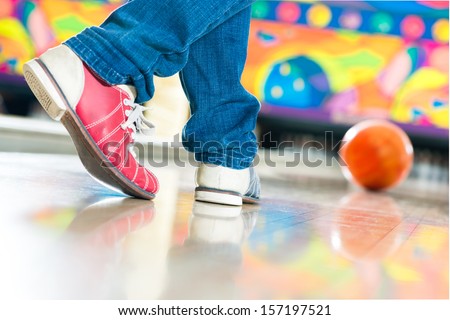 Young man in bowling alley having fun, the sporty man playing a bowling ball in front of the tenpin alley