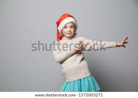 Funny and playful girl in the winter look dancing on the grey backdrop