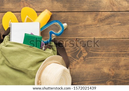 Travel planning concept. Flat lay backpack with blank notebook and traveler accessories on wooden background. Copy space Holiday travel summer background