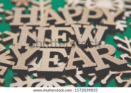 Green Happy New Year background.Wooden alphabet letters and hand made snow flakes made from natural ecological material.Eco friendly home decor for winter holidays