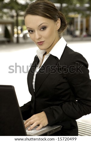 young and attractive brunette businesswoman working on laptop outdoors