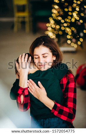 Portrait of mother with son in knitted Christmas sweaters in  play with decor. Winter New Year mood
