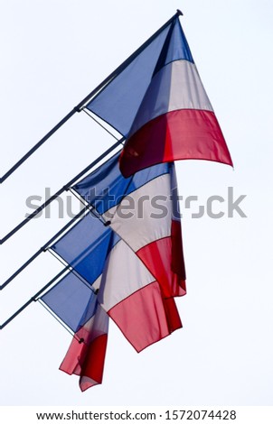 Four Flags of France called "Tricolore" in blue white red "bleu blanc rouge" in Paris with white Sky on a cloudy Day
