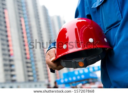 Worker holding a helmet with background of  blurred construction site. 