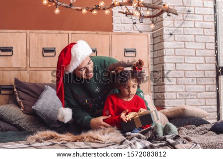 Happy African-American man and his little daughter with gift at home on Christmas eve