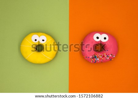 Yellow and red donuts with eyes on color background isolated 