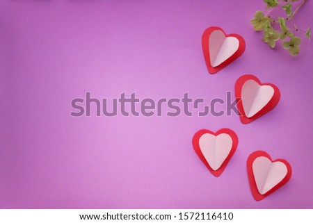 There are many red and pink hearts on the purple background. Valentin's Day, top view.