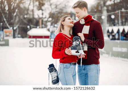 Couple in a ice arena. Elegant girl in a red sweater.