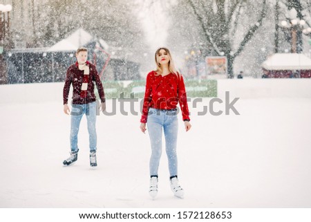 Couple in a ice arena. Elegant girl in a red sweater.