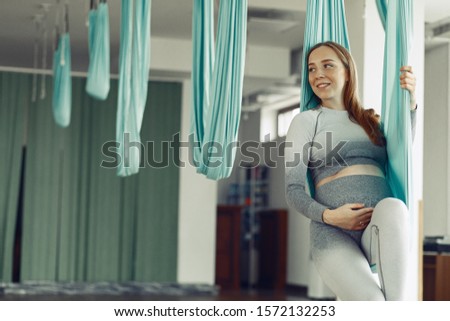Pregnant girl in a gym. Sports girl in a sportswear. Woman in a fly yoga