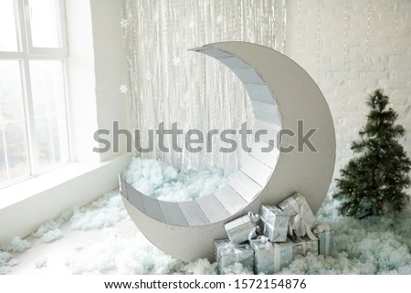 christmas decor silver moon, green tree and gifts near window
