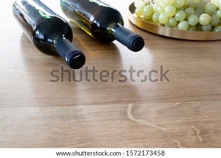 Bunch of grapes and a bottle of organic wine on a wooden table as a background. Front perspective view. Copy space in front of the picture.