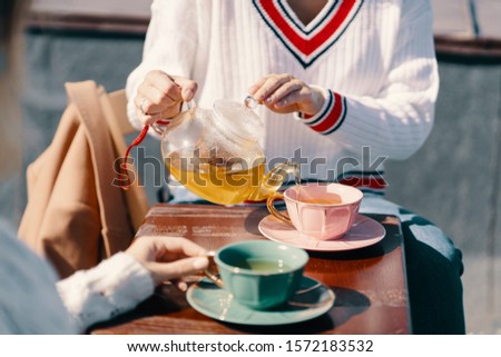 Two attractive girls enjoy a tea party. Drinking healthy buckwheat tea. Healthcare or herbal medicine concept. Close-up on mugs