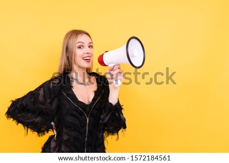 Portrait of young beautiful girl on yellow background, woman shouting into megaphone, studio portrait. People sincere emotions lifestyle concept.