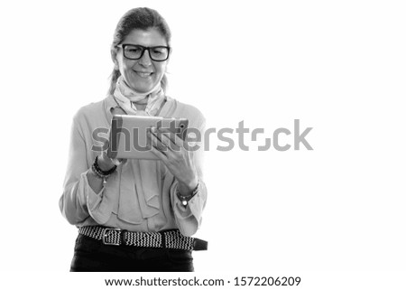 Studio shot of mature happy businesswoman smiling and using digital tablet