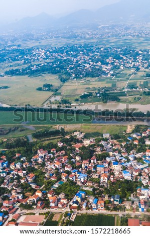 Aerial, vertical landscape photo of a small countryside town near the outskirts of Hanoi, Vietnam. Picture taken in a beautiful sunny autumn evening, out of the airplane windows