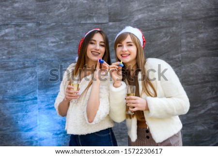Two beautiful girls in fur jackets and champagne celebrating New Year
