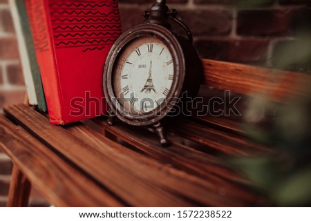 old antique broken clock without arrows with the image of the eiffel tower in a wooden bookcase on the background of books