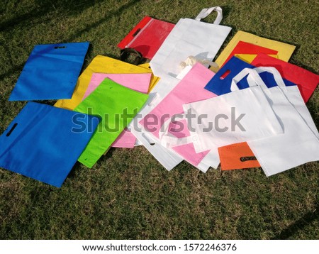 best Assorted Colored Poly Non Woven Bags on Green grass Background 