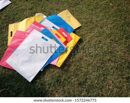 Assorted Colored Poly Non Woven Bags on Green grass Background 